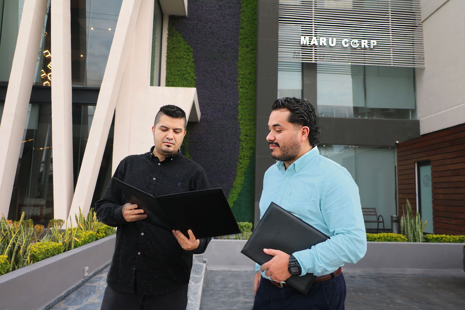 Asesores de MARU CORP revisando documentos frente a sus oficinas